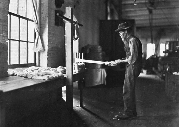 TEXTILE MILL WORKER, 1908. Old man inspecting yarn. Rhodes Manufacturing Company