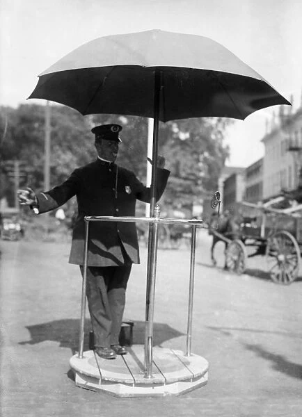 TRAFFIC COP. A traffic cop standing under an umbrella stand while directing traffic