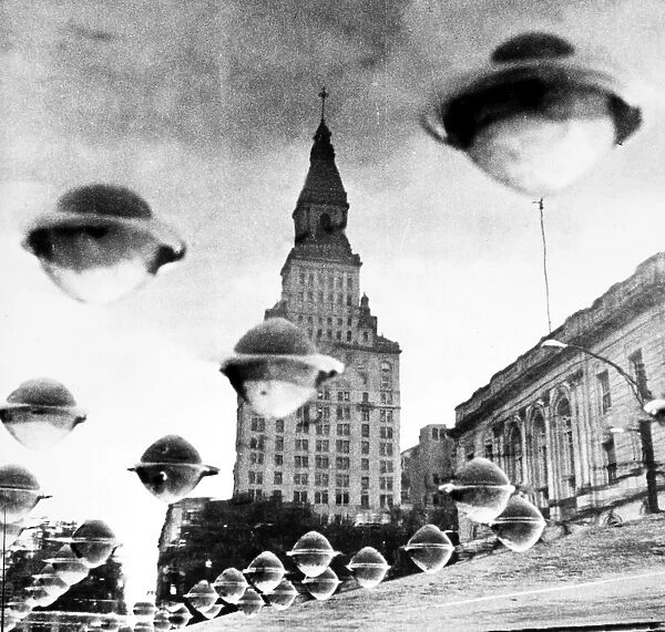 TRAVELERS INSURANCE TOWER. The Travelers Insurance Tower in Hartford, Connecticut seemingly surrounded by flying saucers. Viewed upside down, the UFOs are actually rivets on a bridge girder covered with water. Photographed by Einar Chindmark, 1960