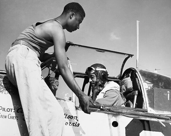 TUSKEGEE AIRMEN, c1943. Alfred Morris, crew chief of the 332nd Fighter Group of the U. S. Army Air Corps, helps his pilot, Captain William Mattison close the canopy of his P-51 Mustang fighter plane just before take-off, in Italy, c1943