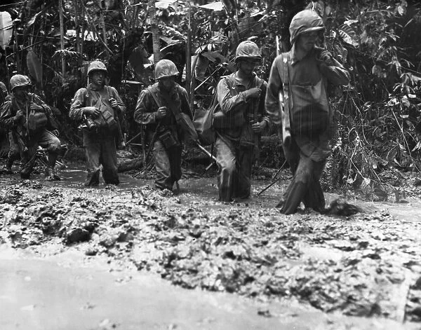 U. S. Marines march through mud on their way to the front lines on Bougainville Island, New Guinea, 4 November 1943