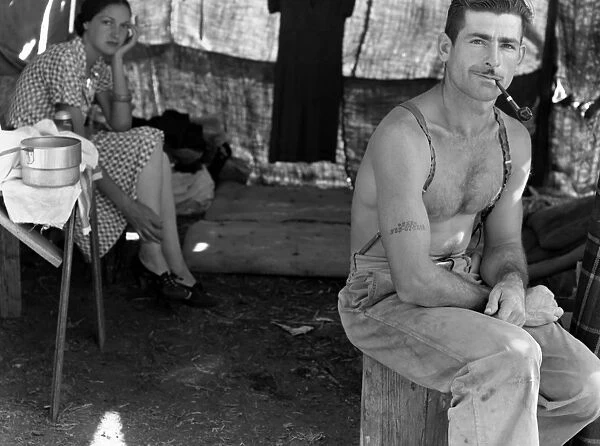 An unemployed lumberjack with his wife in a migrant workers camp for the bean harvest, Marion County, Oregon. The man has his social security number tattooed on his arm. Photograph by Dorothea Lange, August 1939