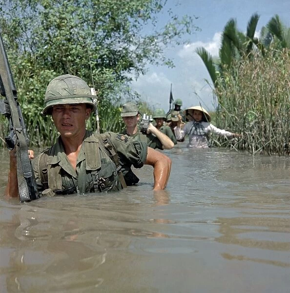 VIETNAM WAR, 1967. Private Fred Greenleaf crossing an irrigation canal en route