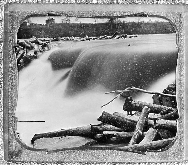A view of the Falls of St. Anthony on the Mississippi River in Minneapolis, Minnesota, partly jammed with logs from a sawmill upstream; Ard Godfrey, who constructed the sawmill in 1849, stands on a log in the foreground. Daguerreotype, c1852, by Tallmadge Elwell