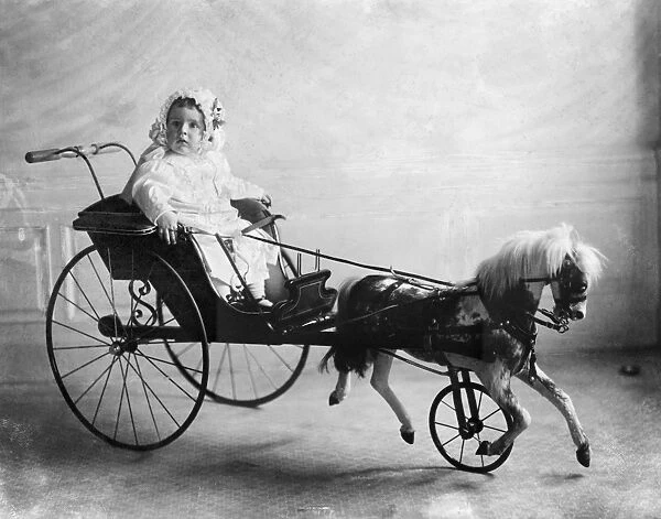 Vinson Walsh McLean, son of American heiress and socialite Evalyn McLean, sitting in a toy horse and carriage. Photograph, 1911