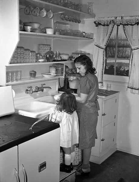 WASHING DISHES, 1942. Three-year-old Ann Heath, daughter of a Warren McArthur factory