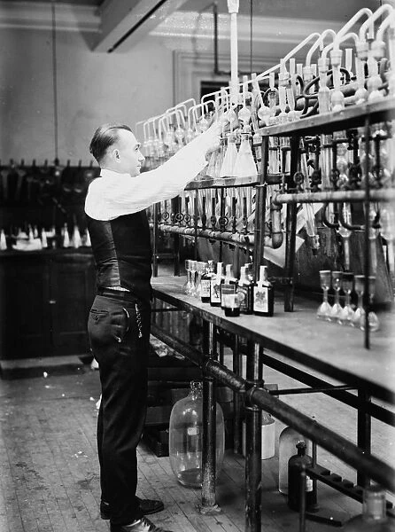 WHISKEY TESTING, 1920. A chemist of the Internal Revenue Service, testing a half