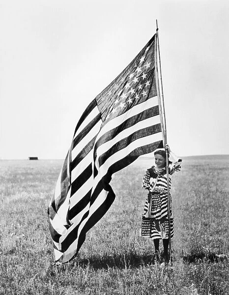 WISCONSIN: PATRIOTISM. A patriotic young woman posing with the American flag on the Wisconsin prairie, c1900