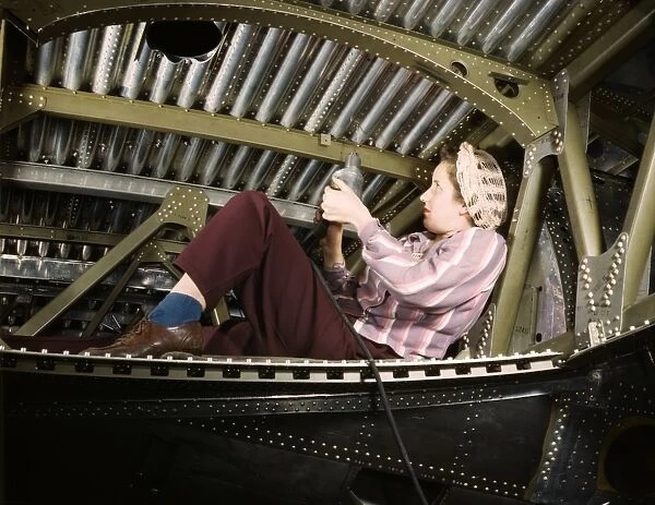A woman riveter working on an A-20 Havoc light attack bomber at the Douglas Aircraft Company plant in Long Beach, California, October 1942. Photographed by Alfred T. Palmer