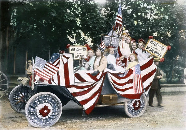 WOMENs SUFFRAGE, 1920. Young girls at an American suffrage meeting, c1920, in an automobile festooned with banners and placards reading, Votes for Us When We are Women