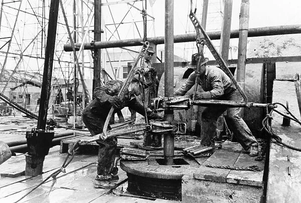 Workers loosening sections of pipe with clamps at an oil well in Kilgore, Texas. Photograph by Russell Lee, April 1939