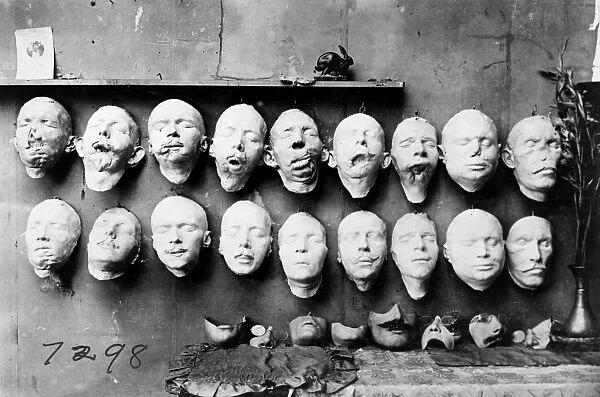 WORLD WAR I: MASKS, 1918. Masks showing the work done by Anna Coleman Ladd of the American Red Cross. The top row are casts taken from soldiers mutilated faces, the bottom row shows masks of their faces before their injuries, made from pre-war photographs. On the table are masks made to fit over the disfigured part of the face. Photograph, 1918