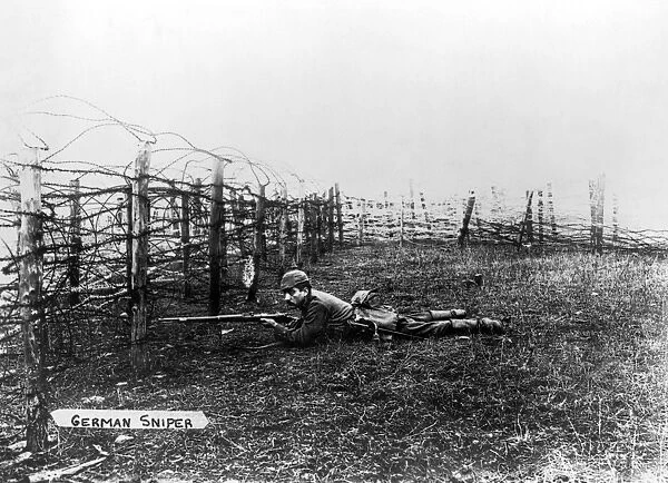 WORLD WAR I: SNIPER. A German sniper positioned on the ground behind barbed-wire