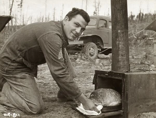 WWII: ALASKA, 1942. Sergeant Al Mangone baking bread in the field during the construction