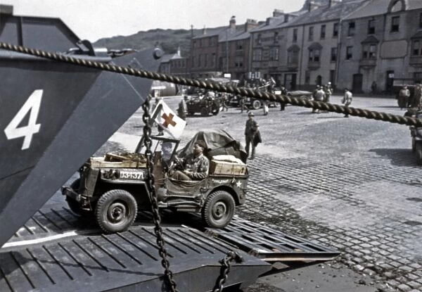 WWII: D-DAY, 1944. American jeeps loading onto a landing ship in a port town in England