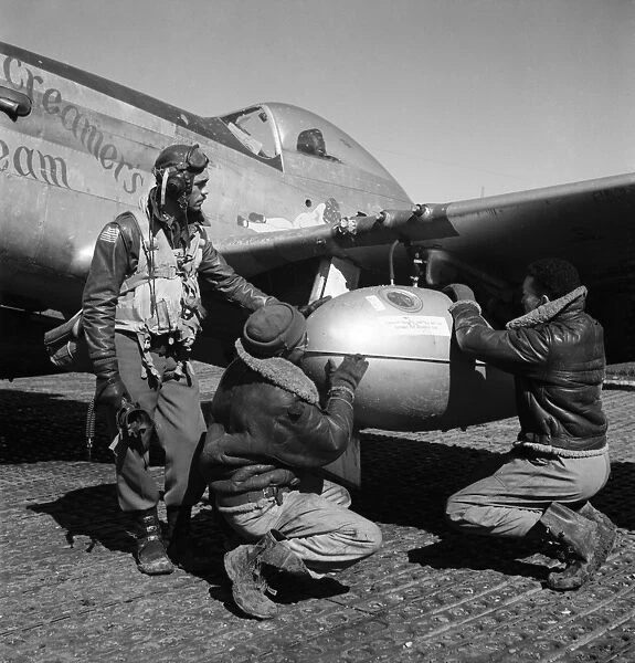 WWII: TUSKEGEE AIRMEN, 1945. Edward Gleed and two other Tuskegee Airmen adjust an external 75 gallon drop tank on the wing of a P-5  /  D fighter plane Creamers Dream, at Ramitelli Airfield, Italy. Photograph by Toni Frissell, March 1945