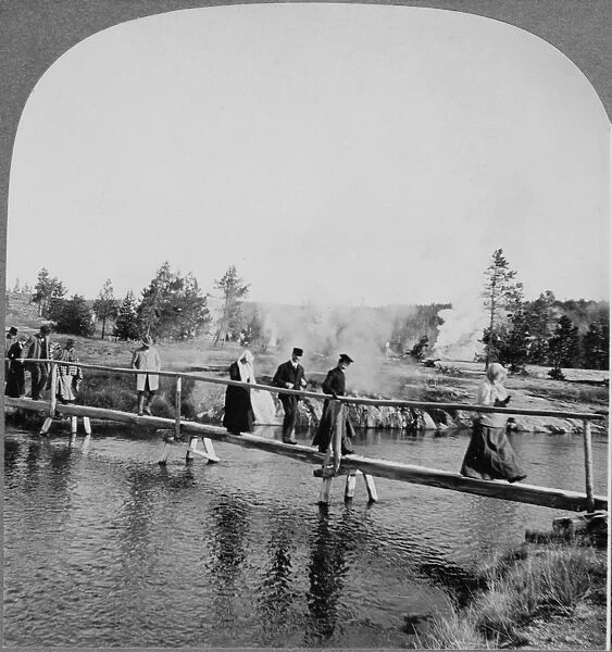 YELLOWSTONE: TOURISTS, c1904. Tourists walking across a footbridge among the geysers