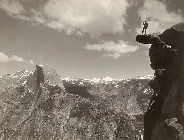 YOSEMITE VALLEY, c1901. A man standing on a overhanging rock facing Half Dome at