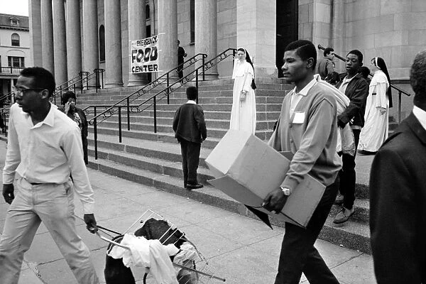 Young black men carrying supplies from a food distribution center at a church in Washington, D. C. 8 April 1968, in the aftermath of rioting that followed the assassination of civil rights leader Martin Luther King, Jr. four days earlier. Photographed by Warren K. Leffler
