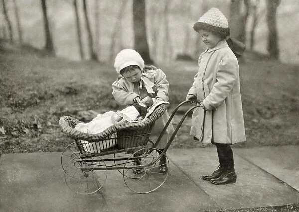 Two young girls playing with a Campbell Kid Doll and a baby carriage in New York City. Photograph by Lewis Hine, March 1912