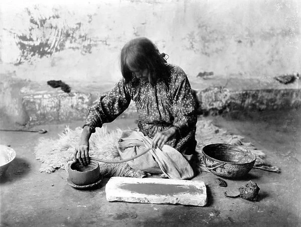 ZUNI POTTER, c1903. A Zuni woman kneeling on an animal skin, forming pottery
