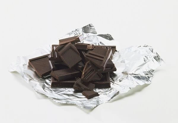 Broken squares of dark chocolate on piece of foil