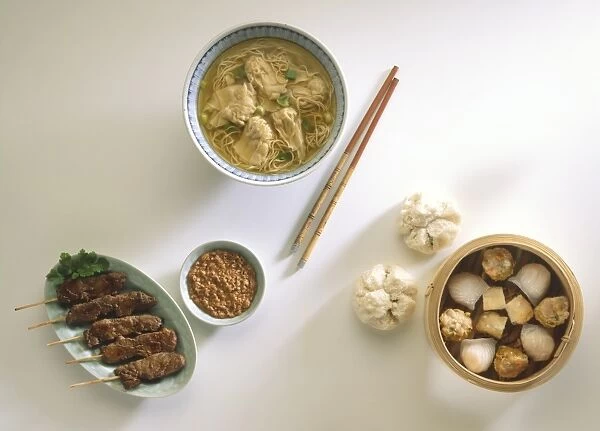 Cantonese wonton soup, selection of dim sum, satay and peanut sauce, and a pair of chopsticks, view from above