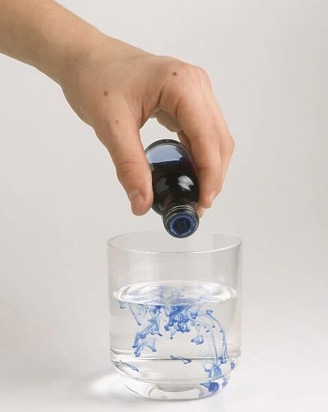 Hand pouring food colouring into glass of water