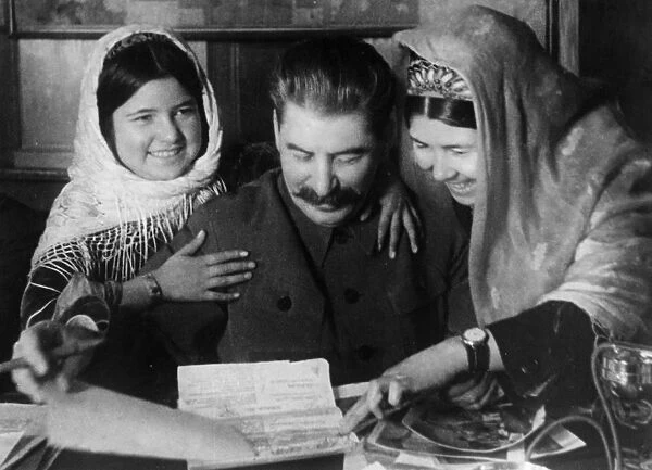 Joseph stalin with two young women from a collective farm in tadjikistan at a conference on cotton farming, january 1935
