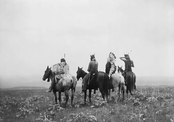 Rear view of four Crow Indians, including Shot in the Hand and Bull Chief, on horseback