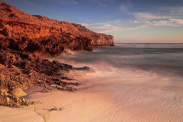 Red glow. Sunset on the coast with red cliffs and warm colours on the beach