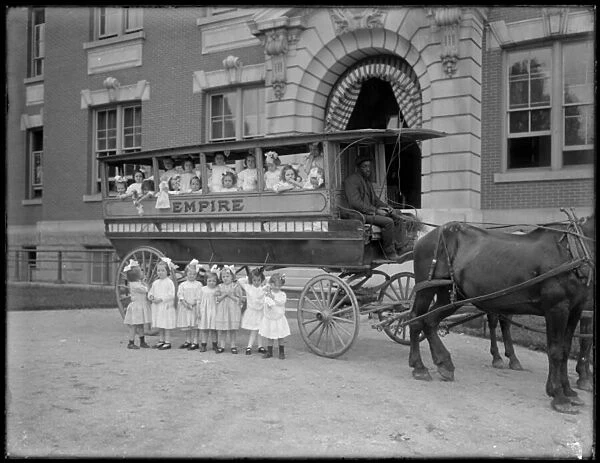 Small girls pose in and in front of a horse-drawn wagon