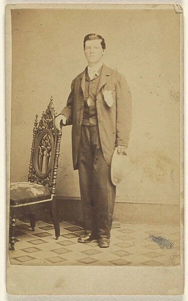 man standing holding hat hand chair back Lew Horning