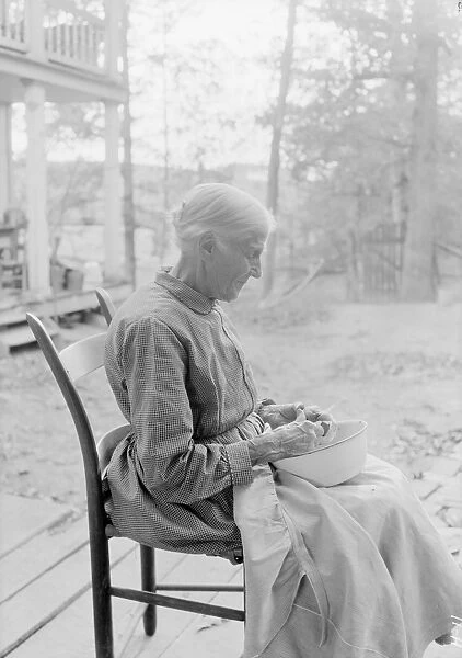 An elder woman cutting fruit on a farm near Bulls Gap, Tennessee, 1933