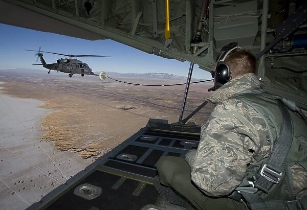 A loadmaster on an HC-130 watches as an HH-60G Pave Hawk refuels