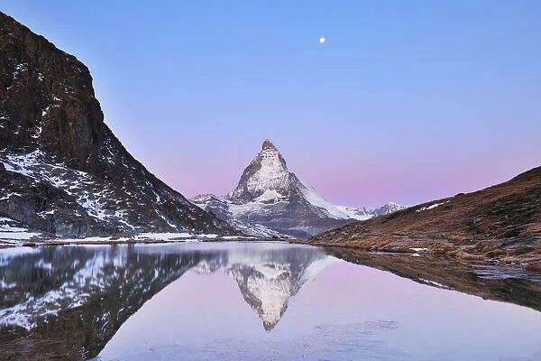 Matterhorn reflected in Lake Riffelsee at Dawn with Moon, Zermatt, Alps, Valais, Switzerland