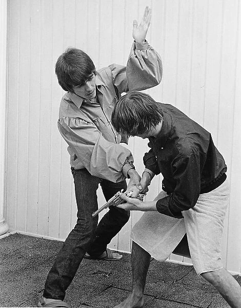 Beatles members George Harrison and Ringo Starr engage stage mock combat at the rented