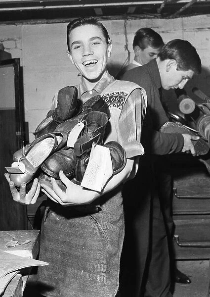A boy carries a bundle of shoes. He is 'at work'