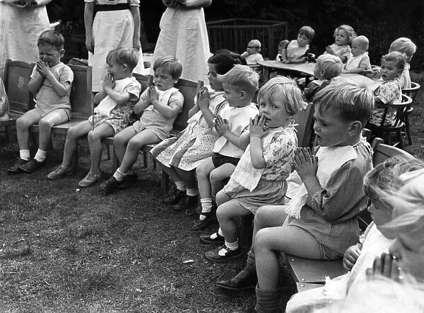 Children saying prayers before dinner time at a nursery in England during the war