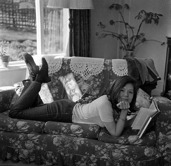 Diana Rigg actress Apr 1965 lying on a sofa at home reading a book