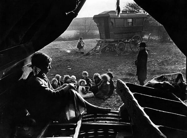Gipsies in camp. View from inside a tent. A woman sits and thinks while a group of