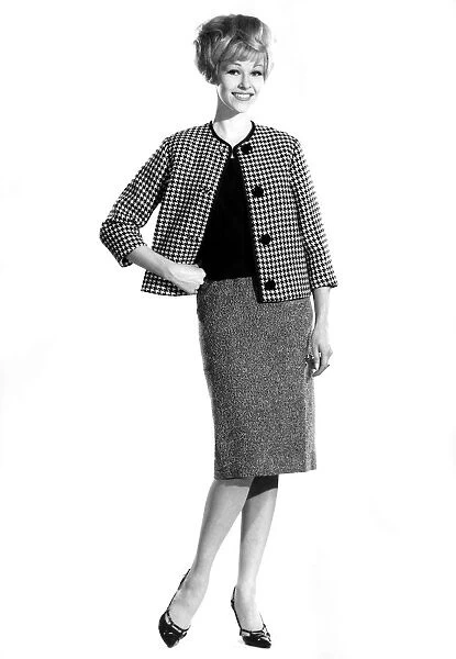 Model Jo Waring wearing skirt with jacket and top, standing with hands on hips