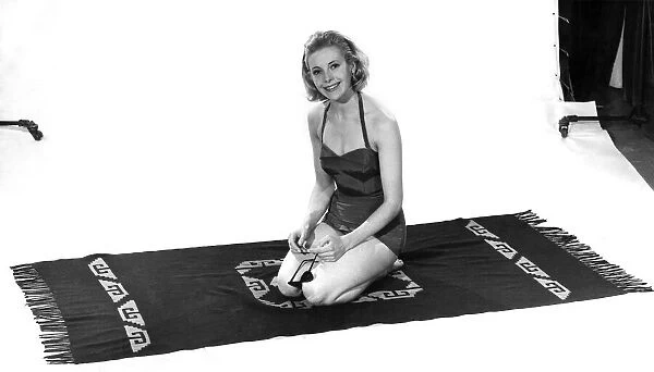 Model wearing a swimsuit kneeling on a towel. April 1961 P008824