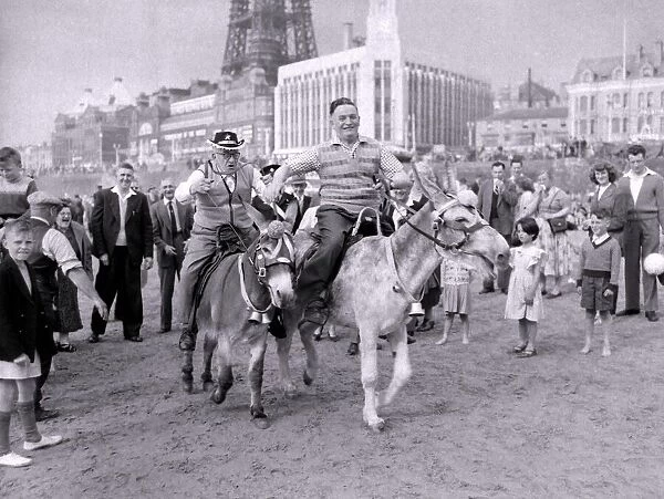The old folks go young for a day. Two men racing donkeys on Blackpool beach. 1959
