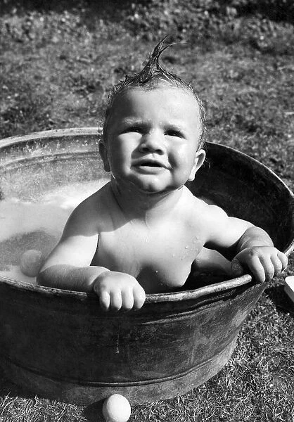 Young toddler having a wash in a tin bath in the back garden in Erith, Kent