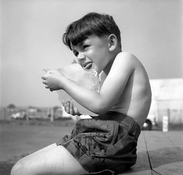 Young Tony Hubbard aged five years old, licking a block of ice to keep cool in the heat