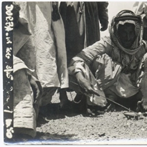 Two Bedouin men cooking lizard, Middle East