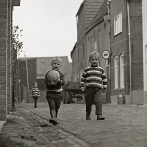 Two boys with a football in the street