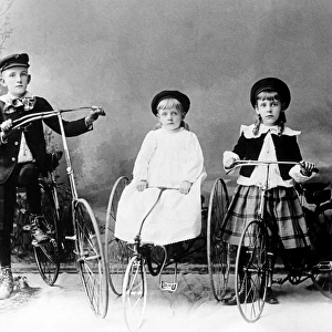 Three children posed with bicycle and tricycles in America