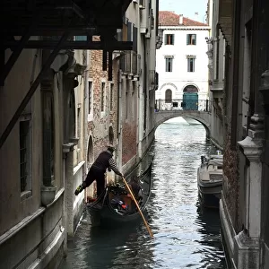 Gondolier fends off boat from a wall with his foot, Venice